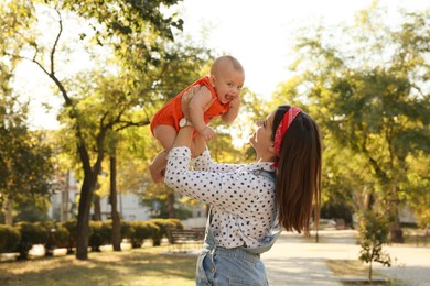 Young mother with her cute baby in park on sunny day