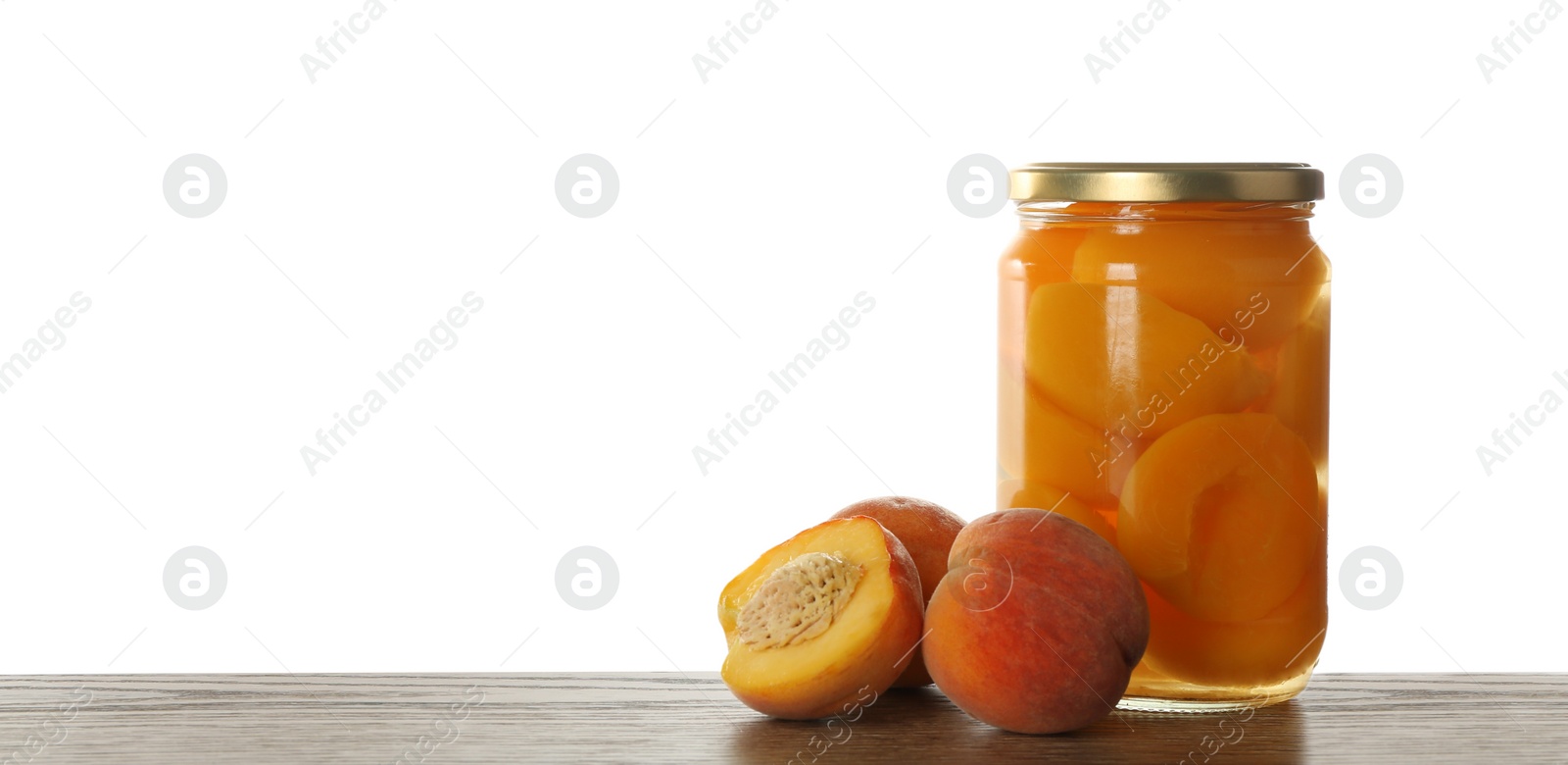 Photo of Glass jar of pickled peaches and fresh fruits on wooden table against white background. Space for text