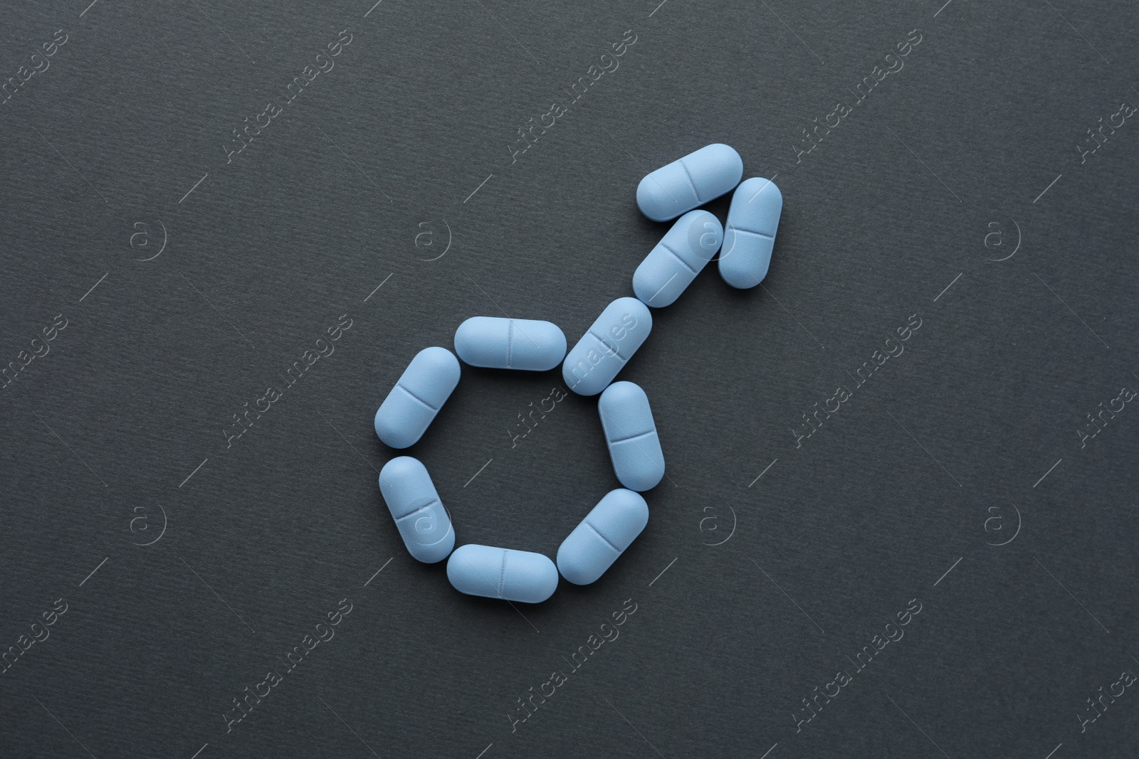 Photo of Male sign made of pills on dark gray background, top view. Potency problem