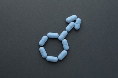 Photo of Male sign made of pills on dark gray background, top view. Potency problem