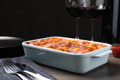 Photo of Tasty cooked lasagna in baking dish on wooden table