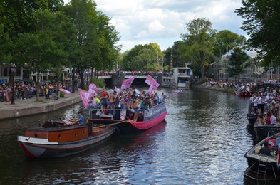 Photo of AMSTERDAM, NETHERLANDS - AUGUST 06, 2022: Many people in boats at LGBT pride parade on river