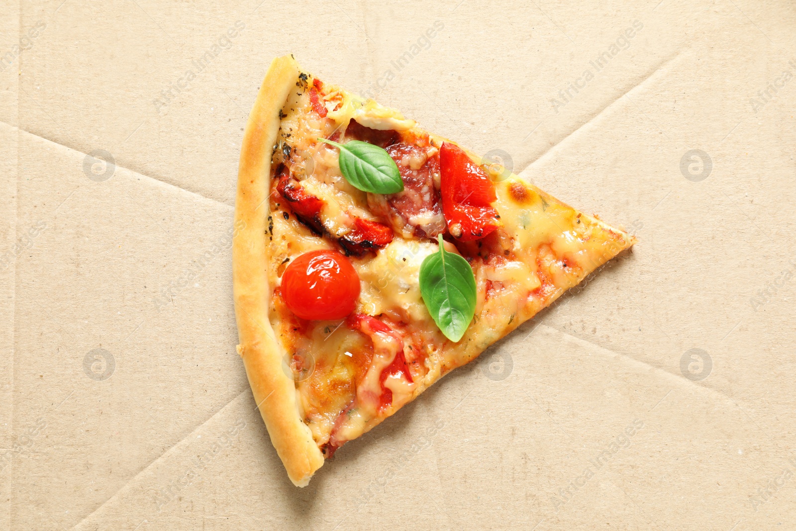 Photo of Last slice of tasty pizza with tomatoes and sausages in cardboard box, top view