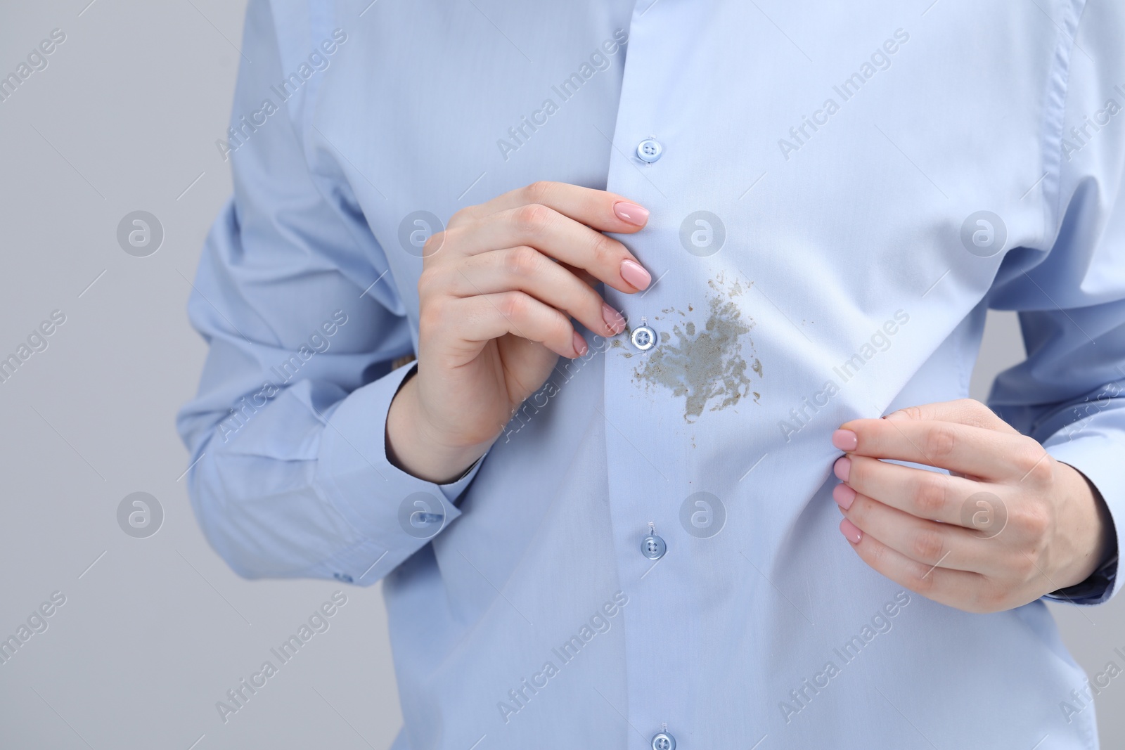 Photo of Woman showing stain on her shirt against light grey background, closeup