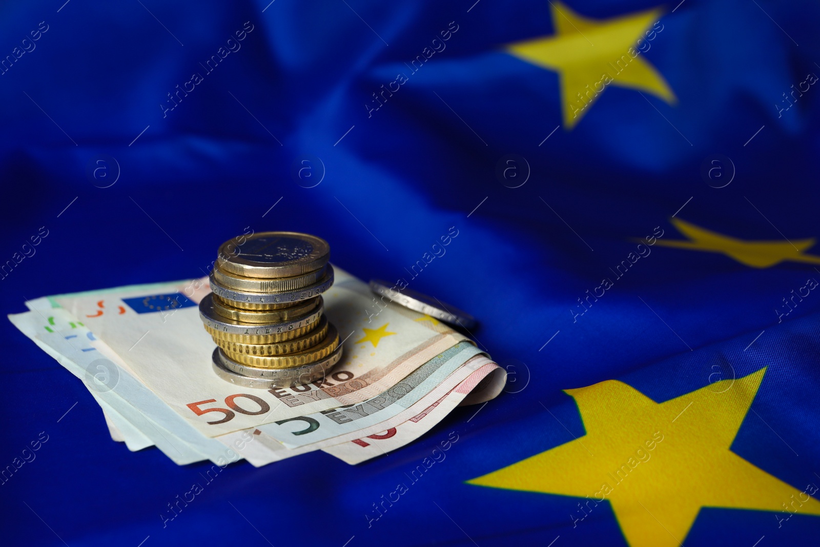 Photo of Stack of coins and banknotes on European Union flag, space for text