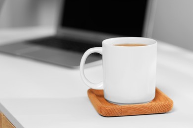 White ceramic mug on table at workplace, space for text