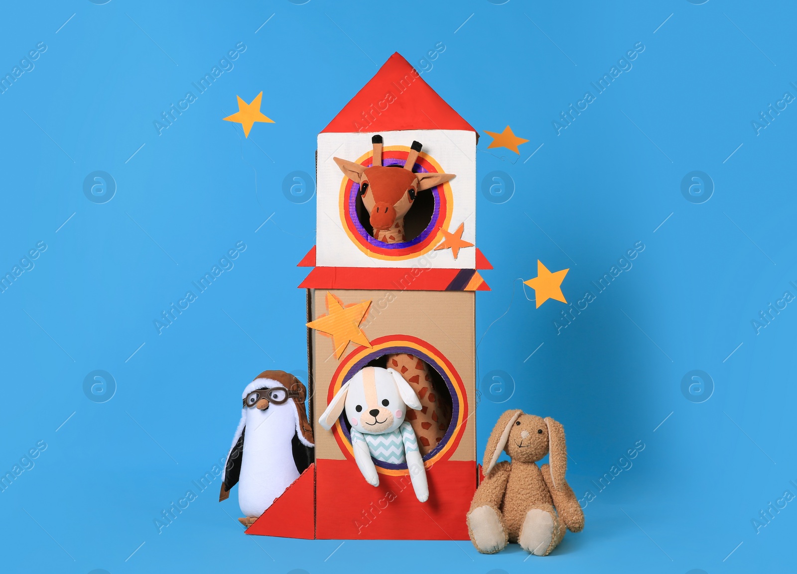 Photo of Cardboard rocket and different toys on light blue background