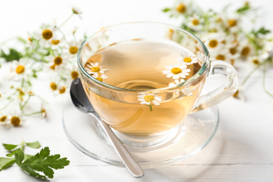 Fresh chamomile tea in cup on white wooden table