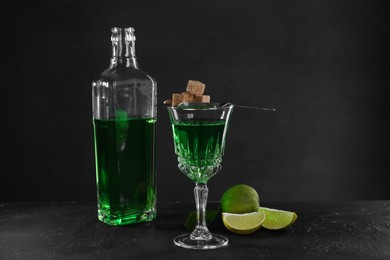 Photo of Absinthe, brown sugar and lime on black table. Alcoholic drink