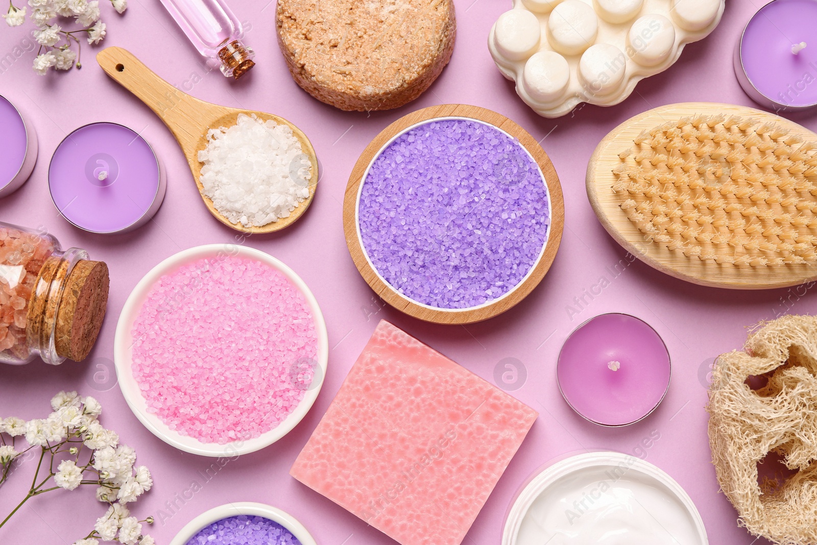 Photo of Sea salt and different spa products on pink background, flat lay