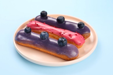 Delicious eclairs covered with glaze on light blue background