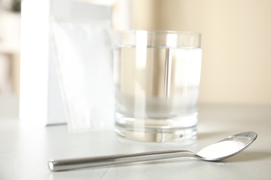 Medicine sachet, glass of water and spoon on light table