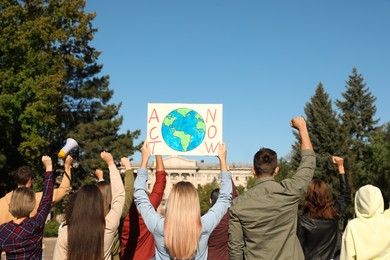 Photo of Group of people with posters protesting against climate change outdoors, back view