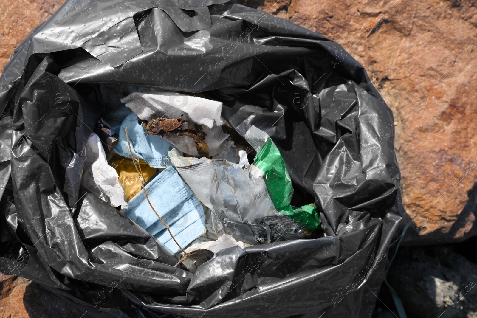 Photo of Trash bag full of garbage outdoors, top view. Environmental Pollution concept