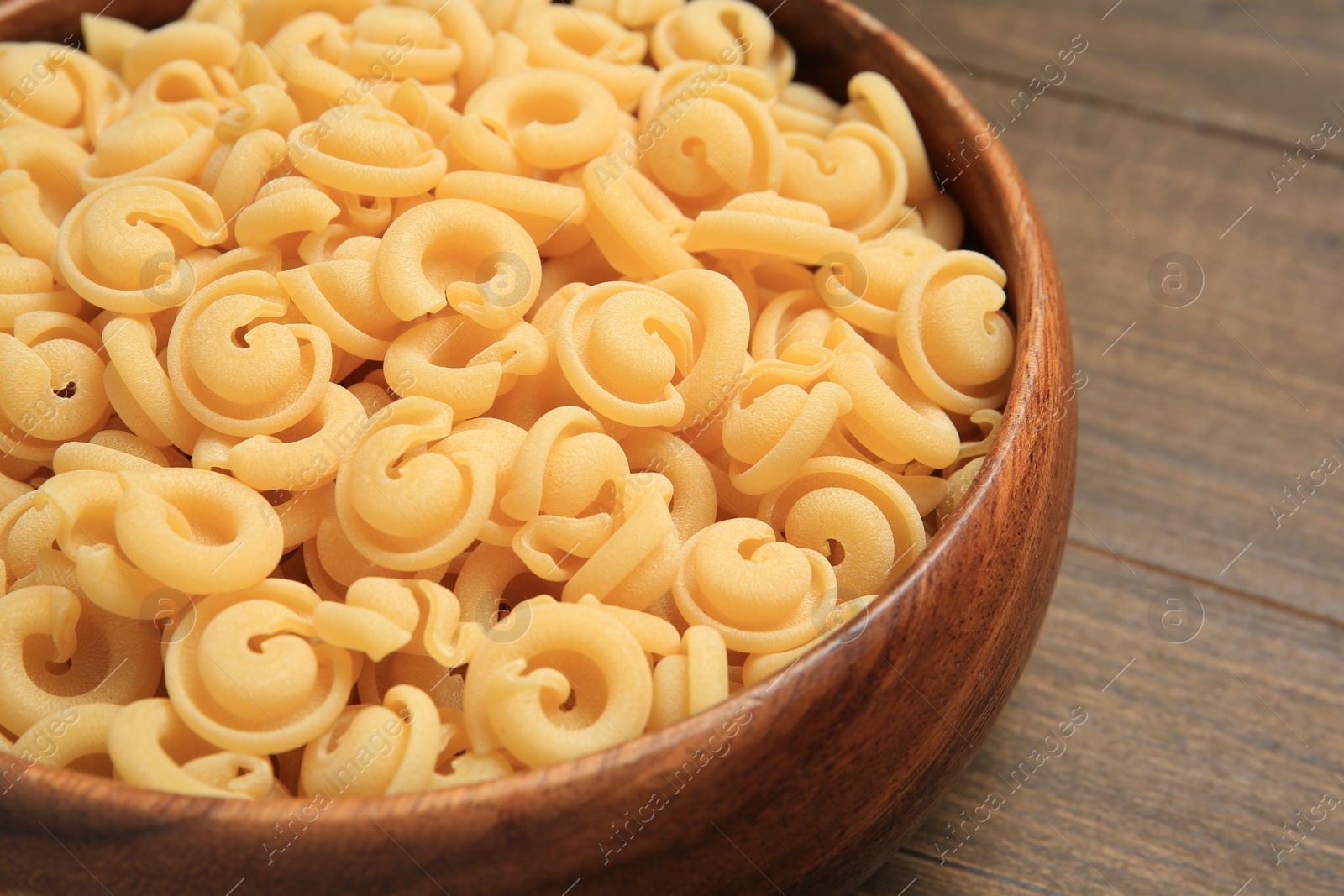 Photo of Raw dischi volanti pasta in bowl on wooden table, closeup