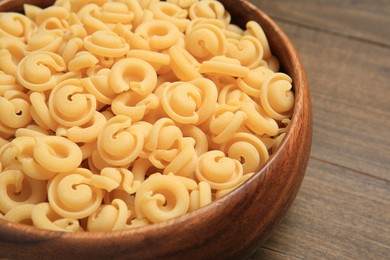 Photo of Raw dischi volanti pasta in bowl on wooden table, closeup