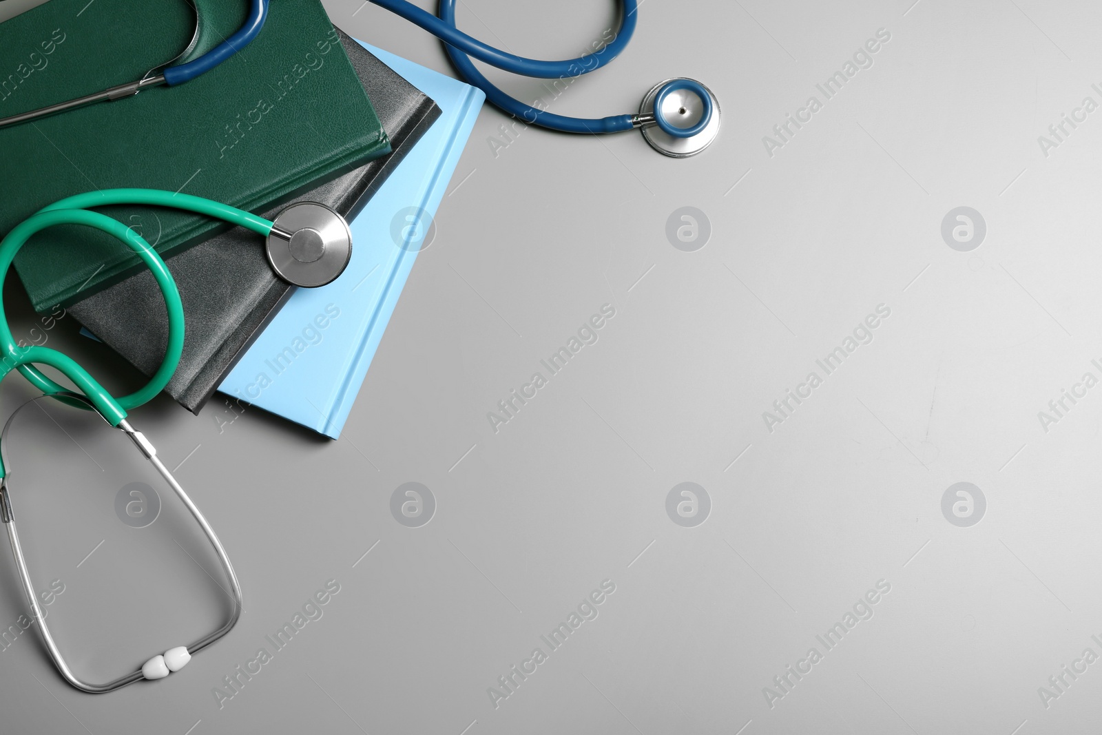 Photo of Student textbooks, stethoscopes and space for text on grey background, top view. Medical education