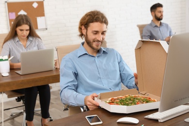 Photo of Office employee having pizza for lunch at workplace. Food delivery