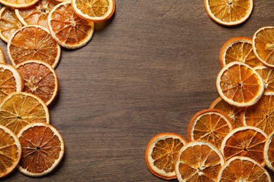 Dry orange slices on wooden table, flat lay. Space for text