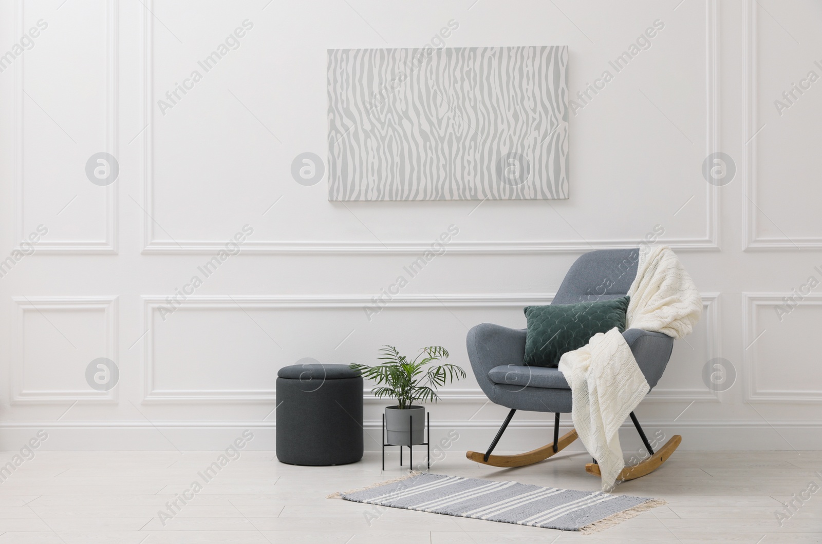 Photo of Stylish room interior with rug, plant and comfortable rocking chair