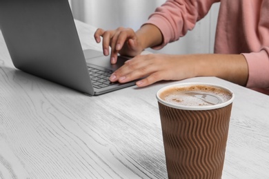 Cardboard coffee cup and blurred woman on background