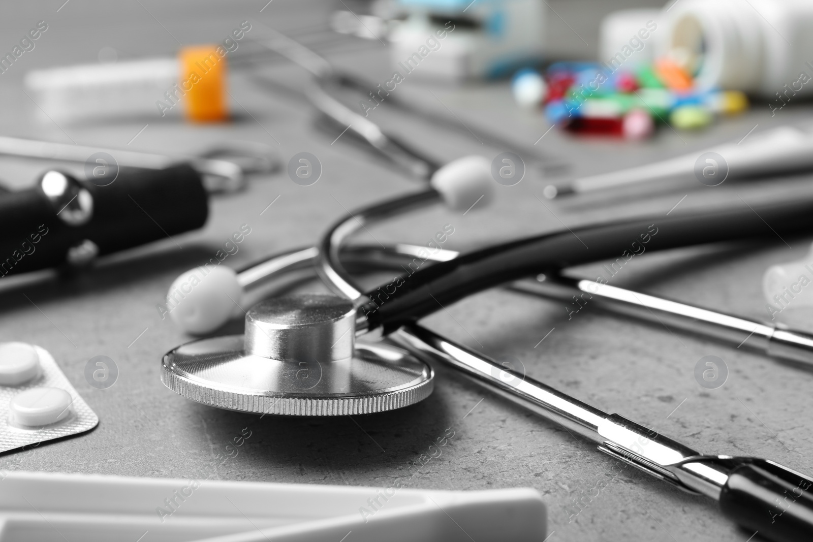 Photo of Stethoscope and different medical objects on grey table, closeup