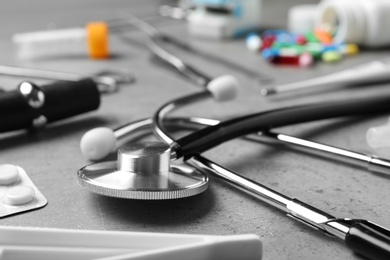 Photo of Stethoscope and different medical objects on grey table, closeup