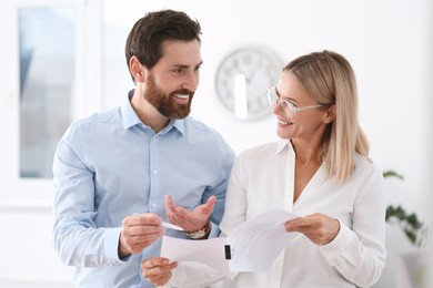 Photo of Happy businesspeople working with documents in office