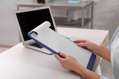 Photo of Doctor with clipboard in clinic, closeup. Patient consultation