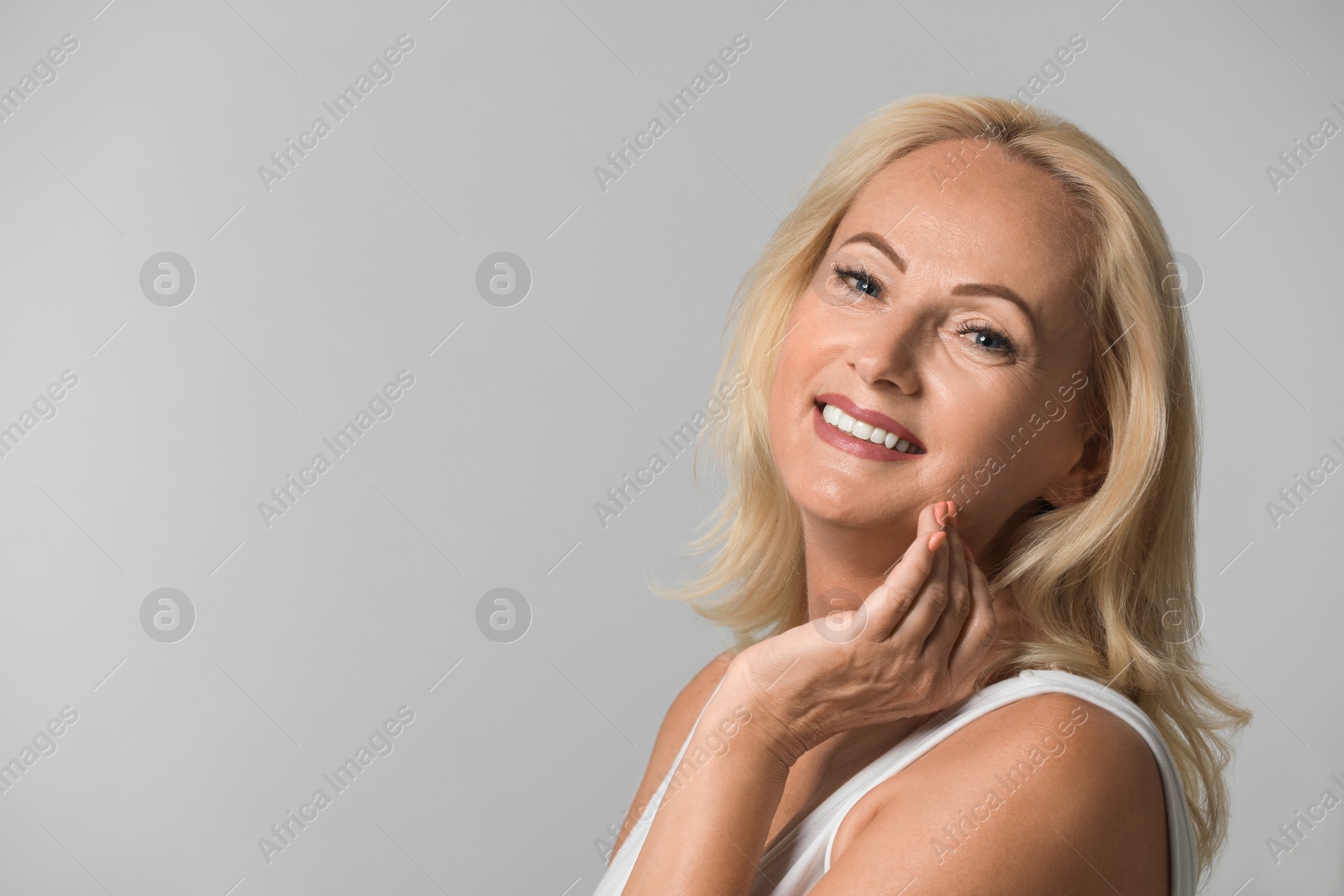 Photo of Portrait of beautiful mature woman with perfect skin on grey background. Space for text