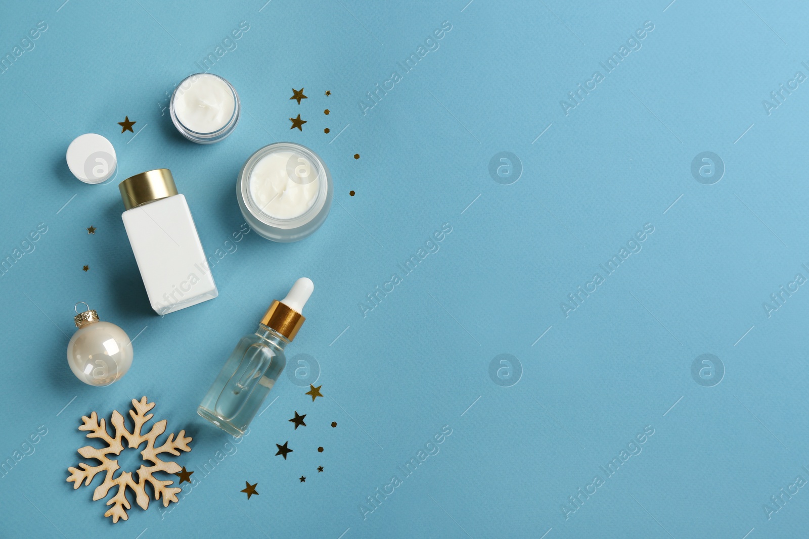 Photo of Flat lay composition with different cosmetic products on light blue background, space for text. Winter care