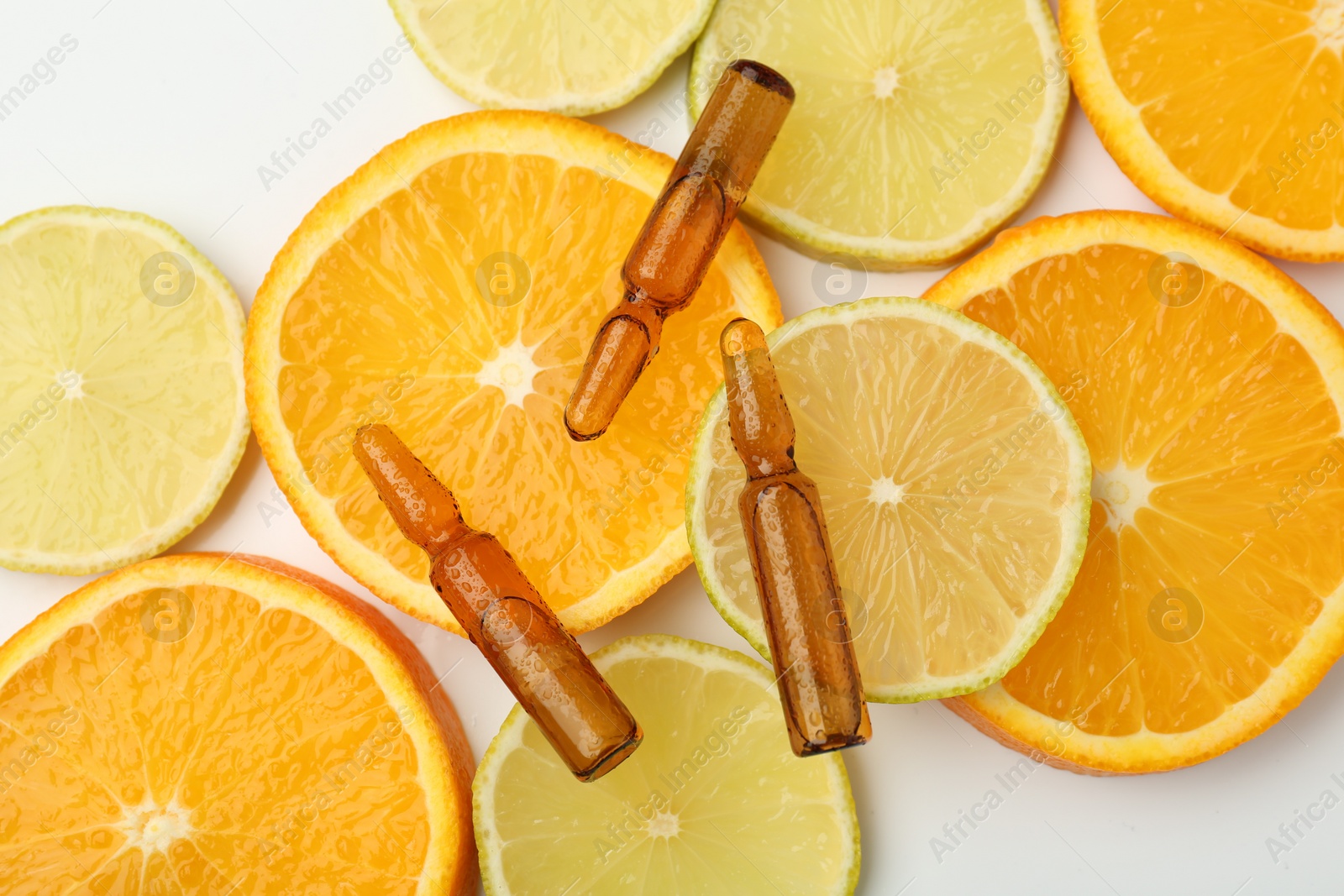 Photo of Skincare ampoules with vitamin C, lemon and orange slices on white background, flat lay