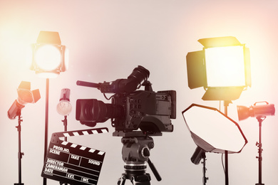 Modern professional video camera and lighting equipment in studio 