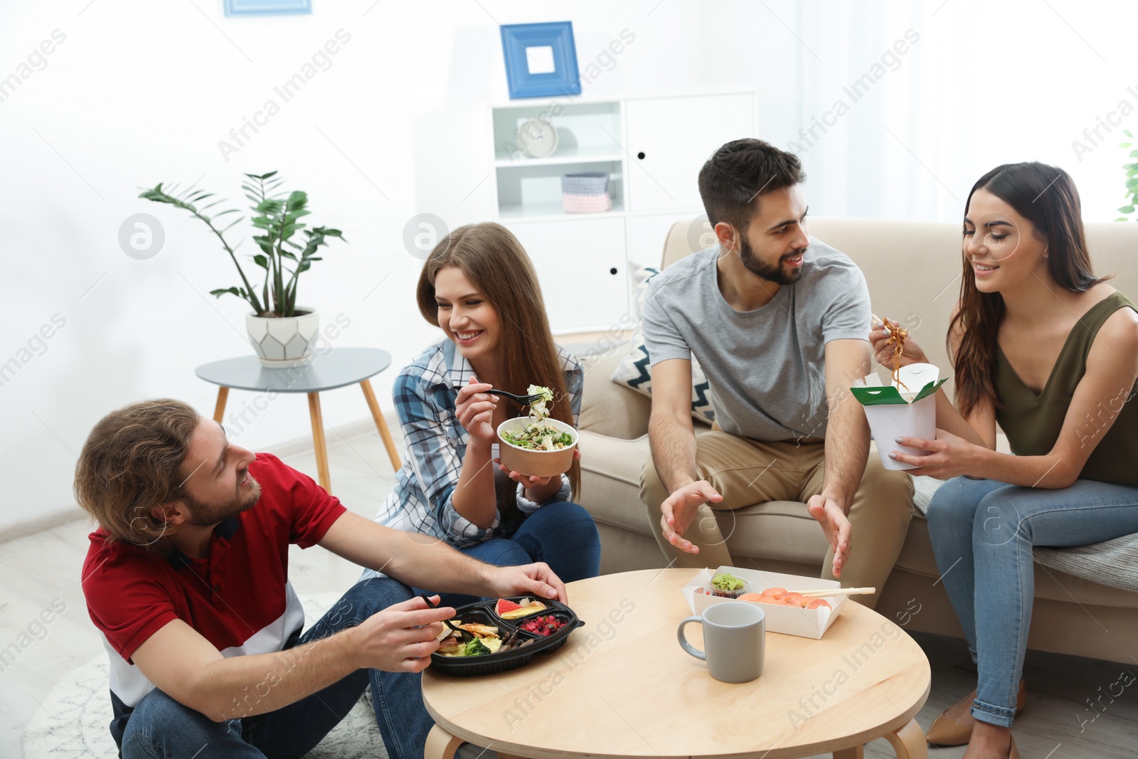 Photo of Young people having lunch together in living room. Food delivery