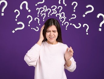 Amnesia. Confused young woman and question marks on purple background