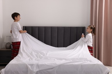 Photo of Brother and sister changing bed linens together in bedroom