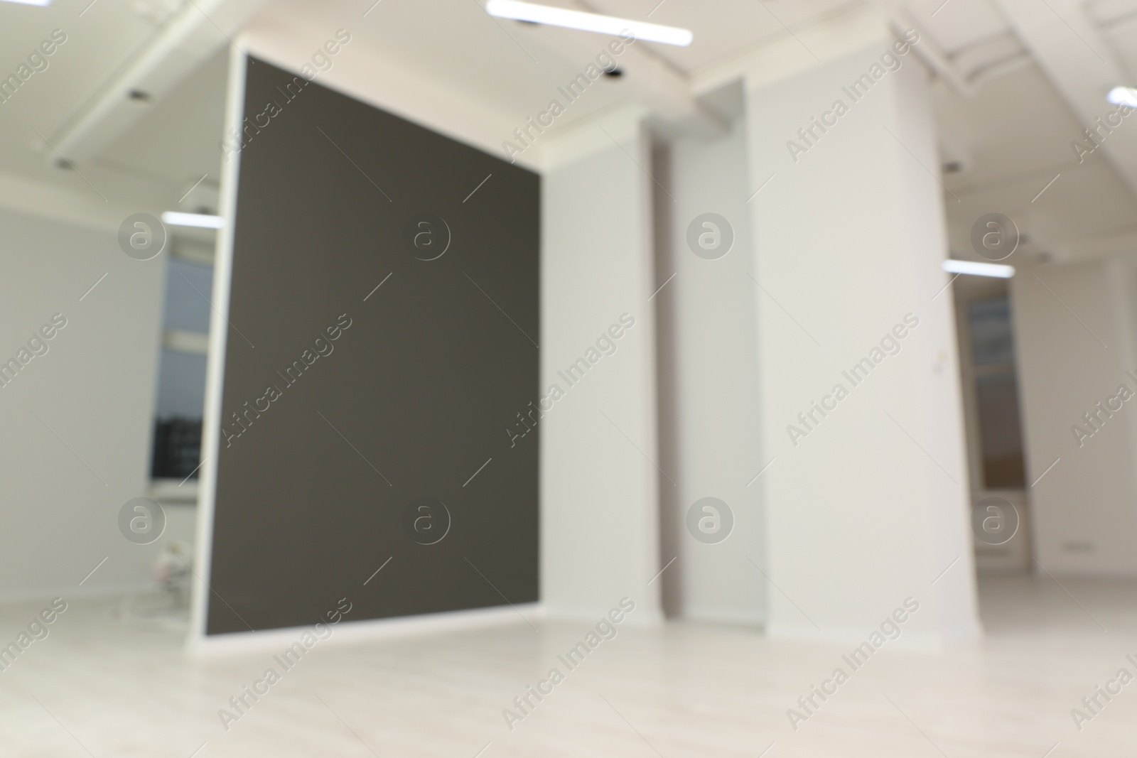 Photo of Blurred view of empty office room with color walls and modern lights on ceiling. Interior design