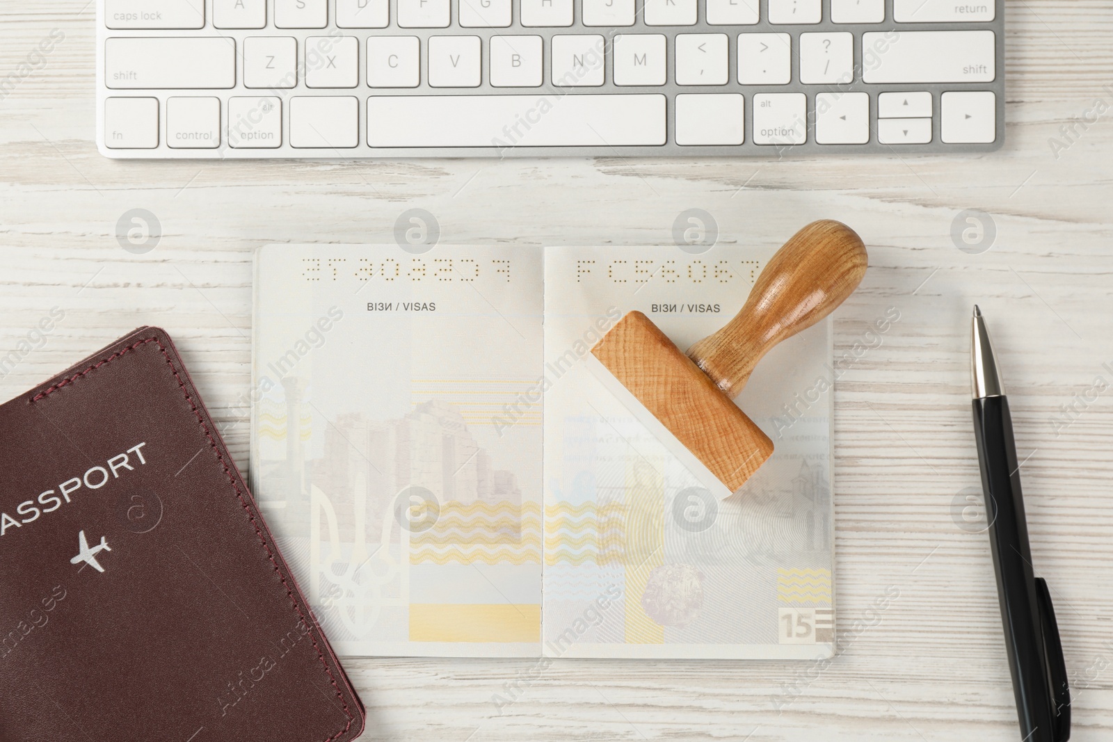 Photo of Moldova, Ceadir-Lunga - June 13, 2022: Passports with blank visa pages, stamp, computer keyboard and pen on white wooden table, flat lay