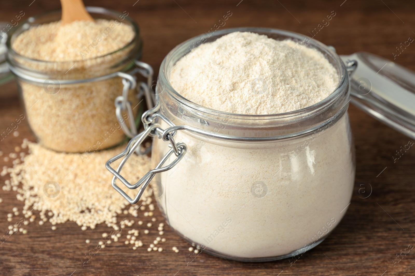 Photo of Jars with quinoa flour and seeds on wooden table, closeup