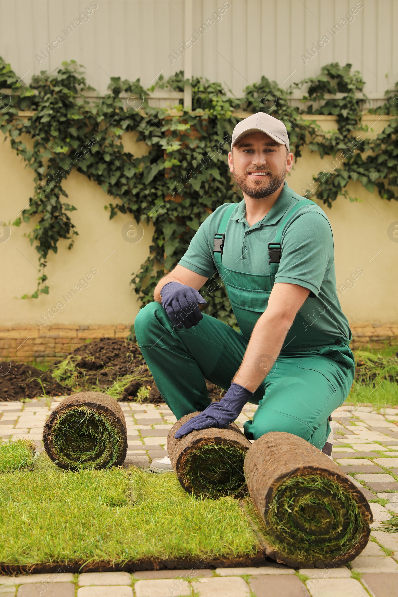 Photo of Worker unrolling grass sods on pavement at backyard