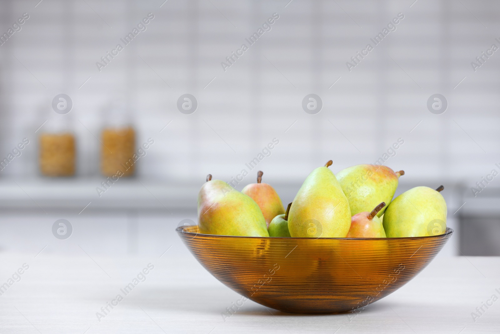 Photo of Fresh ripe pears on white table in kitchen. Space for text