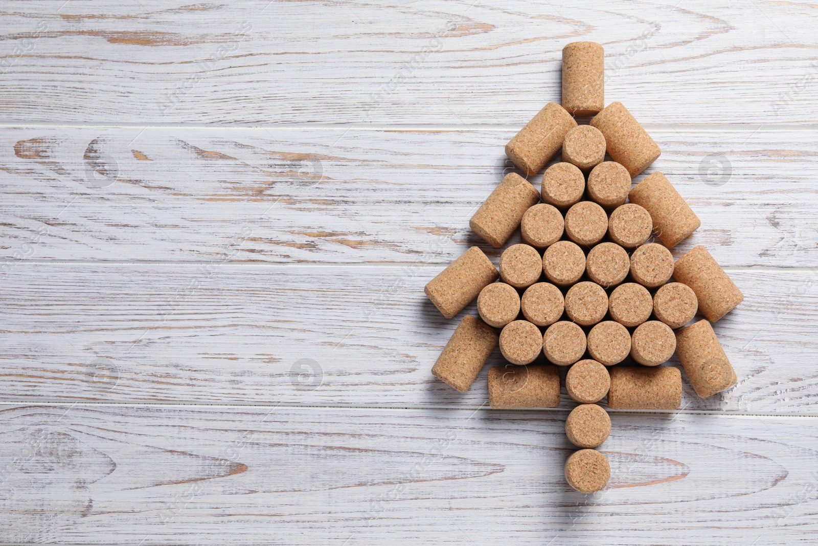 Photo of Christmas tree made of wine corks on white wooden table, top view. Space for text