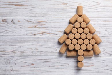 Photo of Christmas tree made of wine corks on white wooden table, top view. Space for text