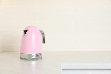 Photo of Modern electric kettle on counter in kitchen. Space for text