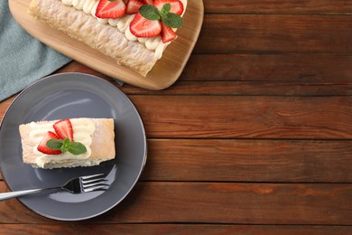 Photo of Delicious cake roll with strawberries and cream on wooden table, top view. Space for text