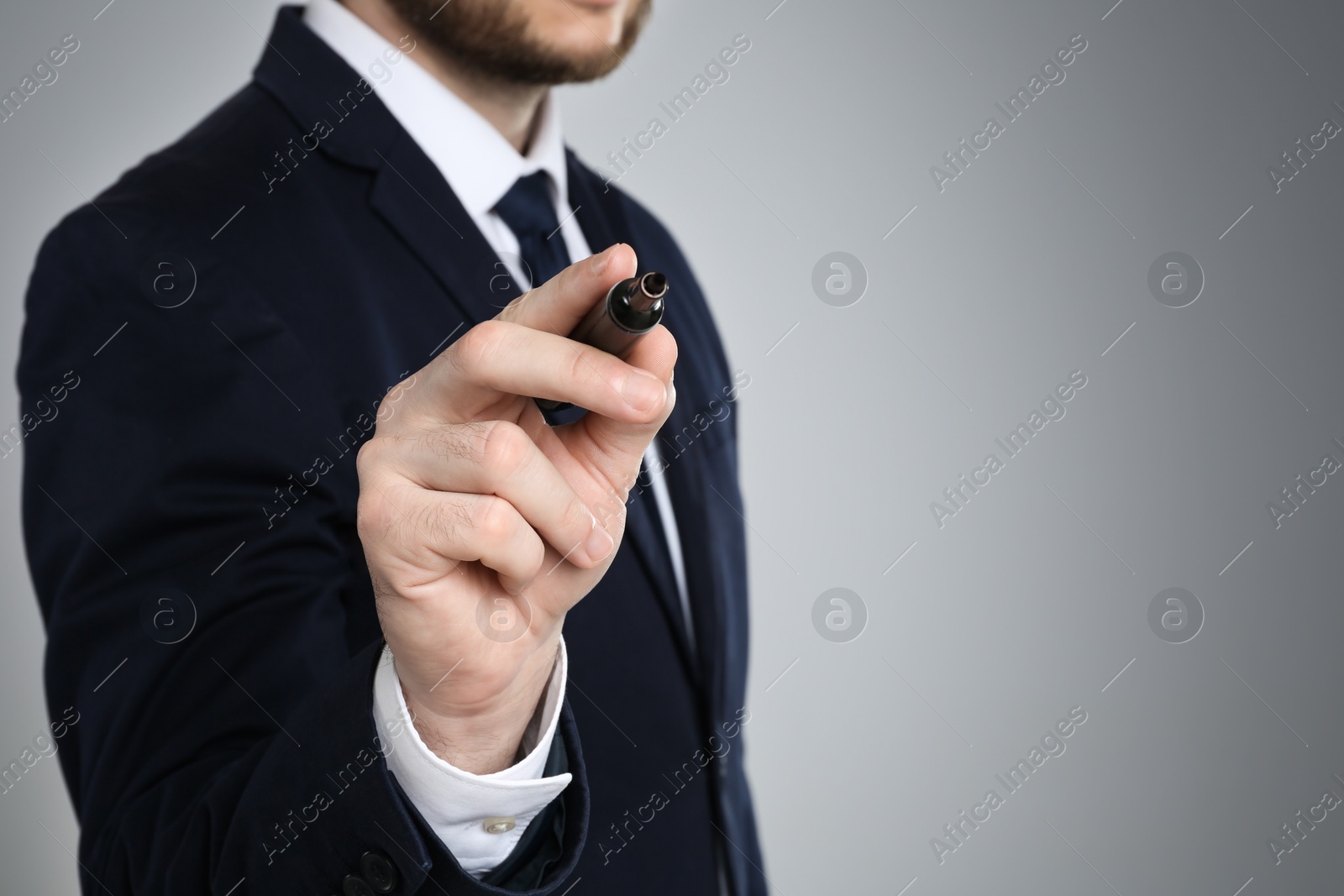 Photo of Businessman with marker against grey background, focus on hand. Space for text
