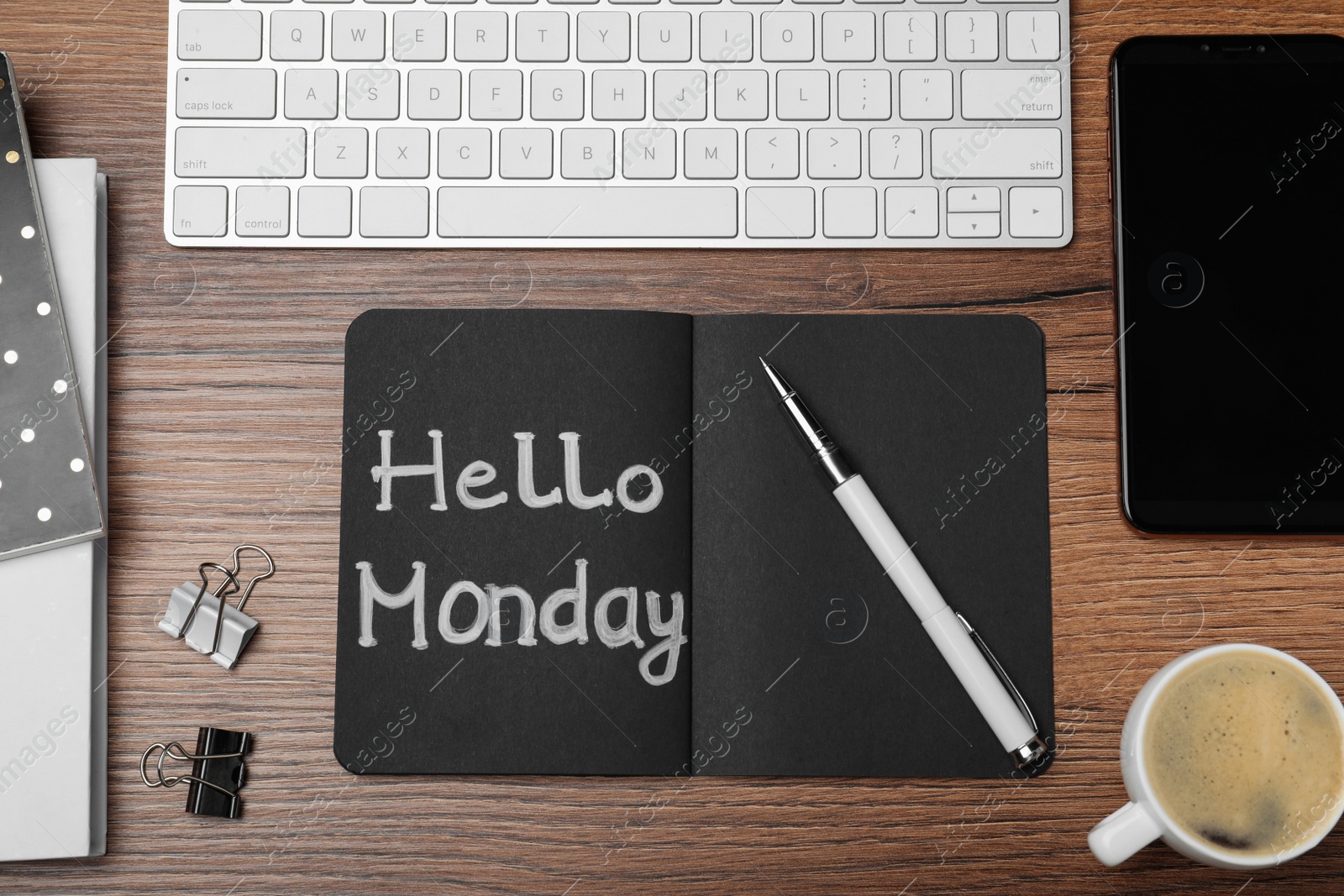 Photo of Message Hello Monday written in black notebook, computer keyboard and cup of coffee on wooden desk, flat lay