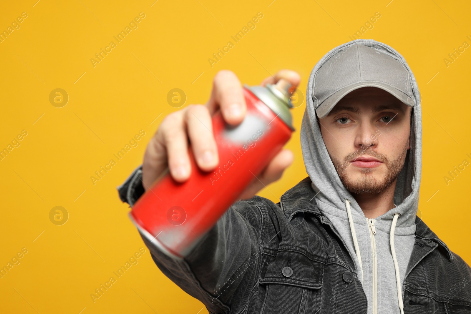 Photo of Handsome man holding can of spray paint on yellow background