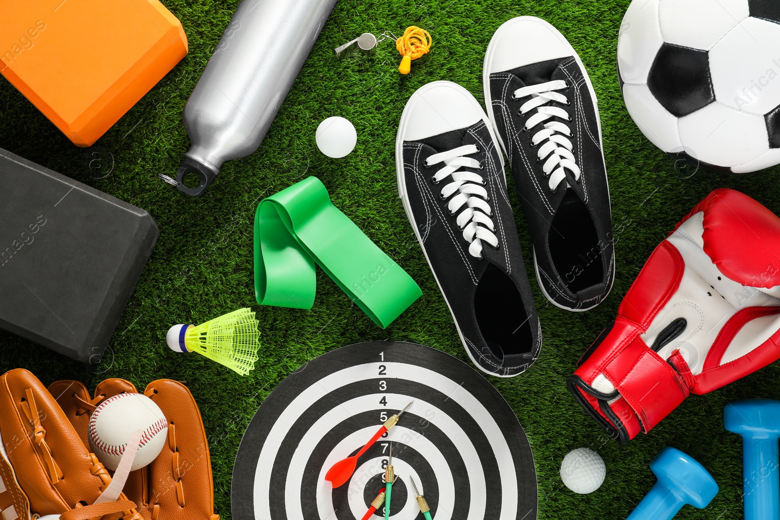 Photo of Different sport equipment and sneakers on green grass, flat lay