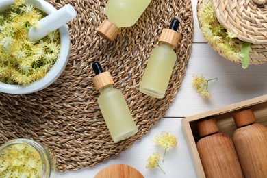 Photo of Flat lay composition with bottles of essential oil and linden flowers on white wooden table